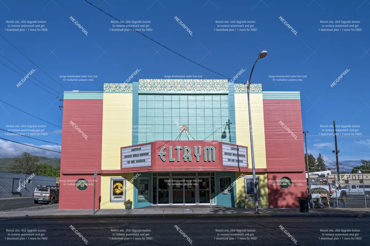 The historic exterior of a theater, adorned with a vintage marquee and bold, colorful facade, stands as a prominent local landmark. Large entrance doors invite visitors in, and the lively ambiance suggests an active community hub.