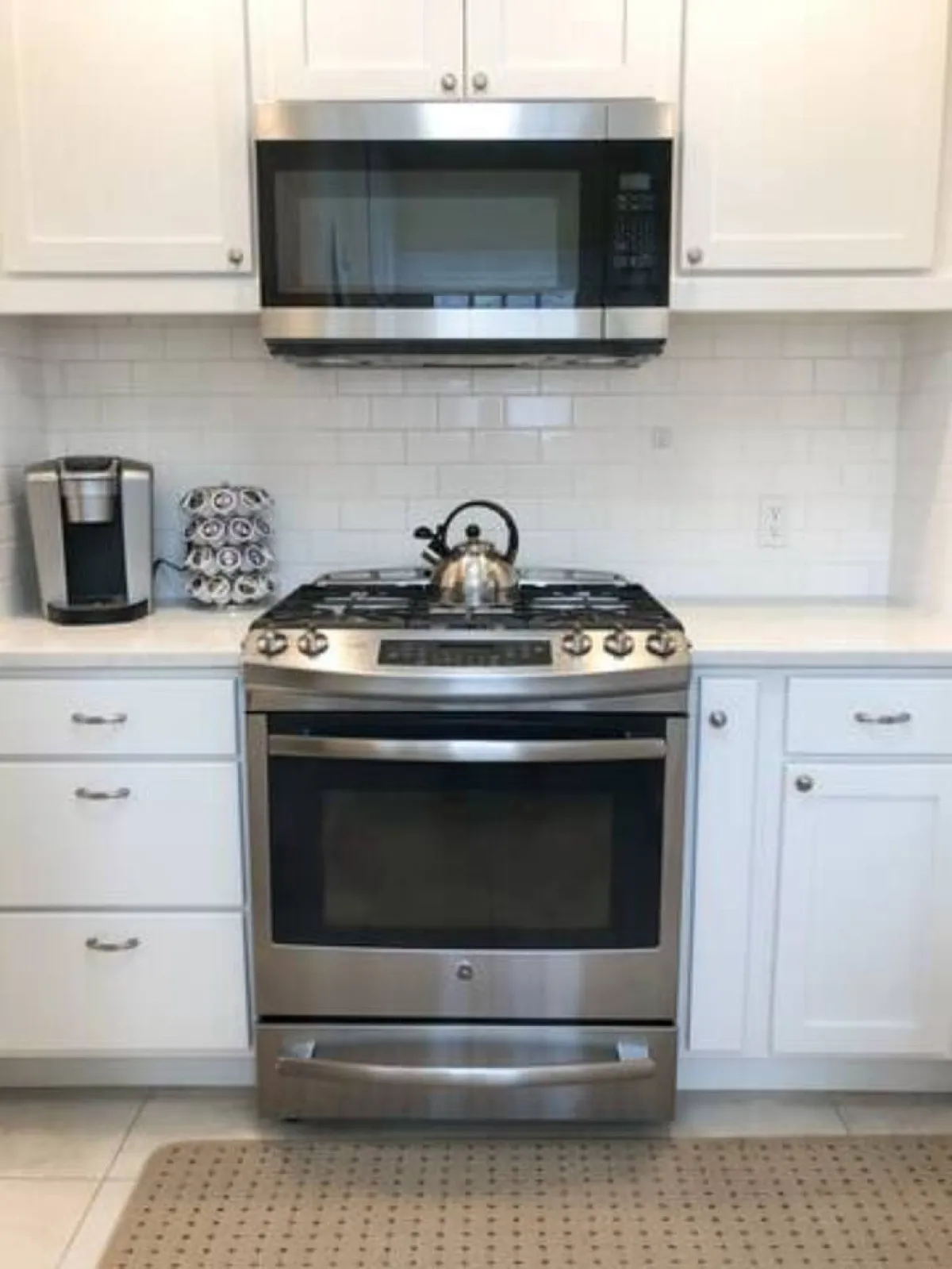 A cozy kitchen corner featuring a stainless steel oven, microwave, coffee maker, and kettle. The arrangement is practical and emphasizes the convenience and self-sufficiency offered to guests.
