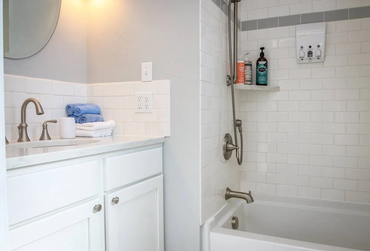 A sparkling, modern bathroom with a stylish sink and faucet, a large mirror, plush towels, and a glimpse of the inviting shower area. The mood is fresh and serene, offering a spa-like environment for guests to refresh themselves.