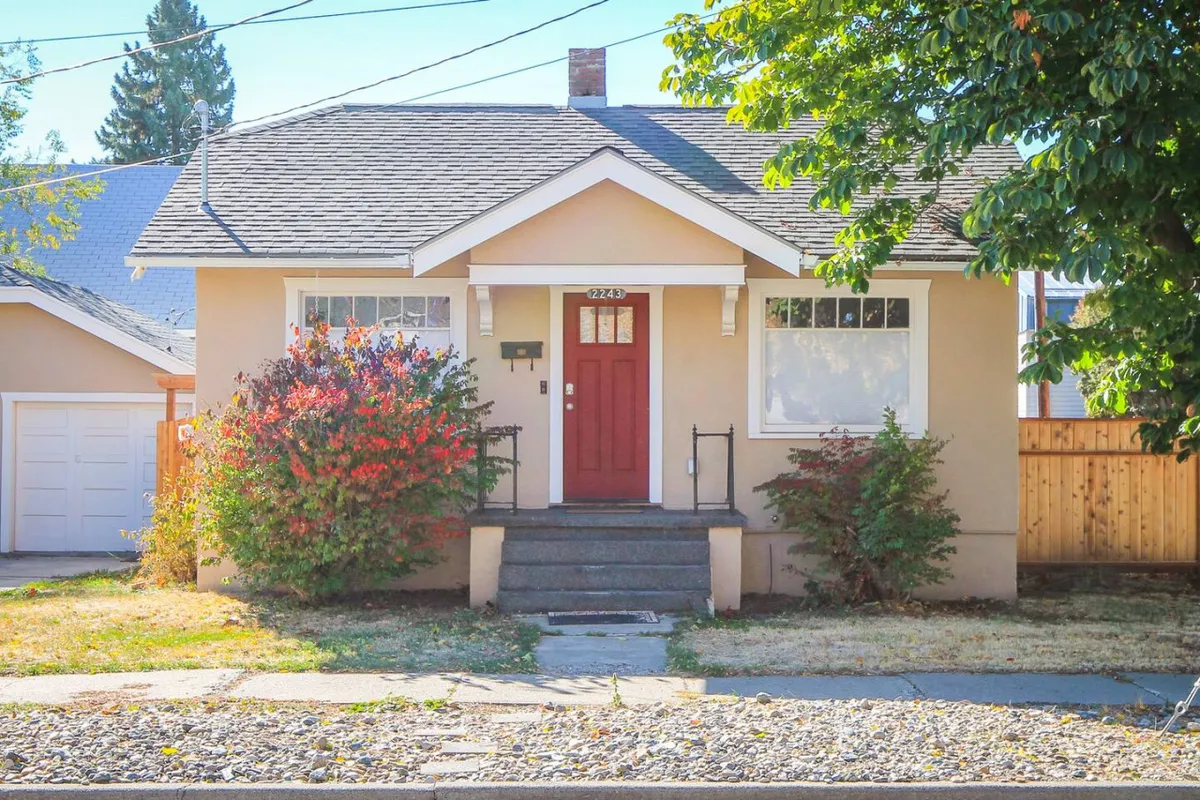 A welcoming exterior of a home features a vibrant red front door and steps flanked by colorful shrubs. The setting feels inviting and cozy, hinting at a warm retreat after time spent outdoors.