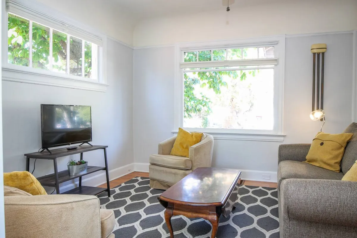 A comfortable seating area with a television, coffee table, and a window allowing natural light to stream in. The overall mood is cozy and welcoming, ideal for movie nights or unwinding after a day out.