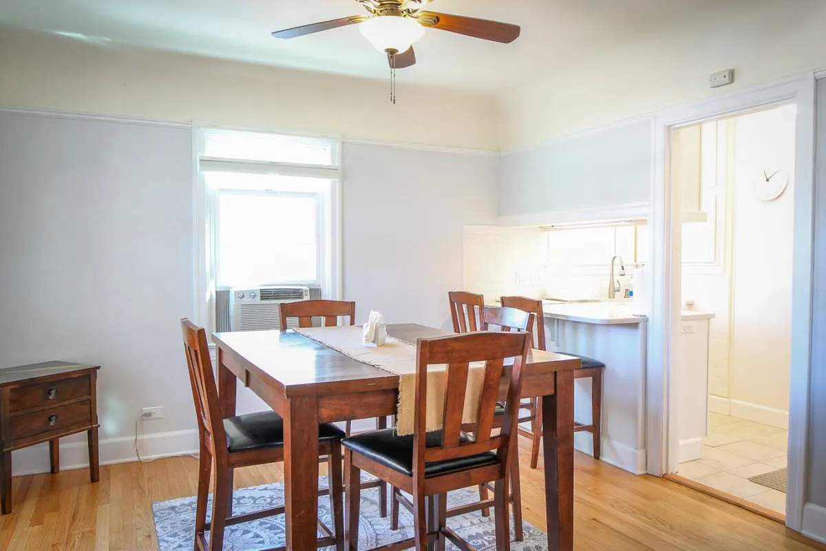 A cozy dining area with a wooden table, ceiling fan, and large window allowing sunlight to flood the space. The setting is perfect for family meals, morning coffee, or planning the day’s adventure.